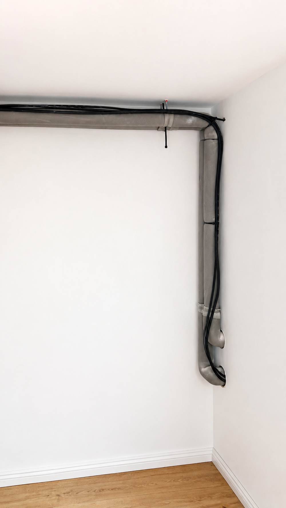Gedämmte Heizungsleitungen und Steuerleitung sauber an der Wand geführt