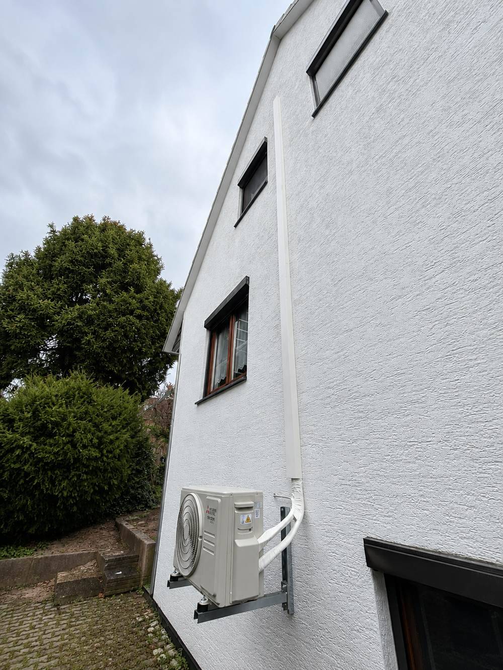 Kältemittelleitungen in weißem Kanal entlang der Fassade geführt