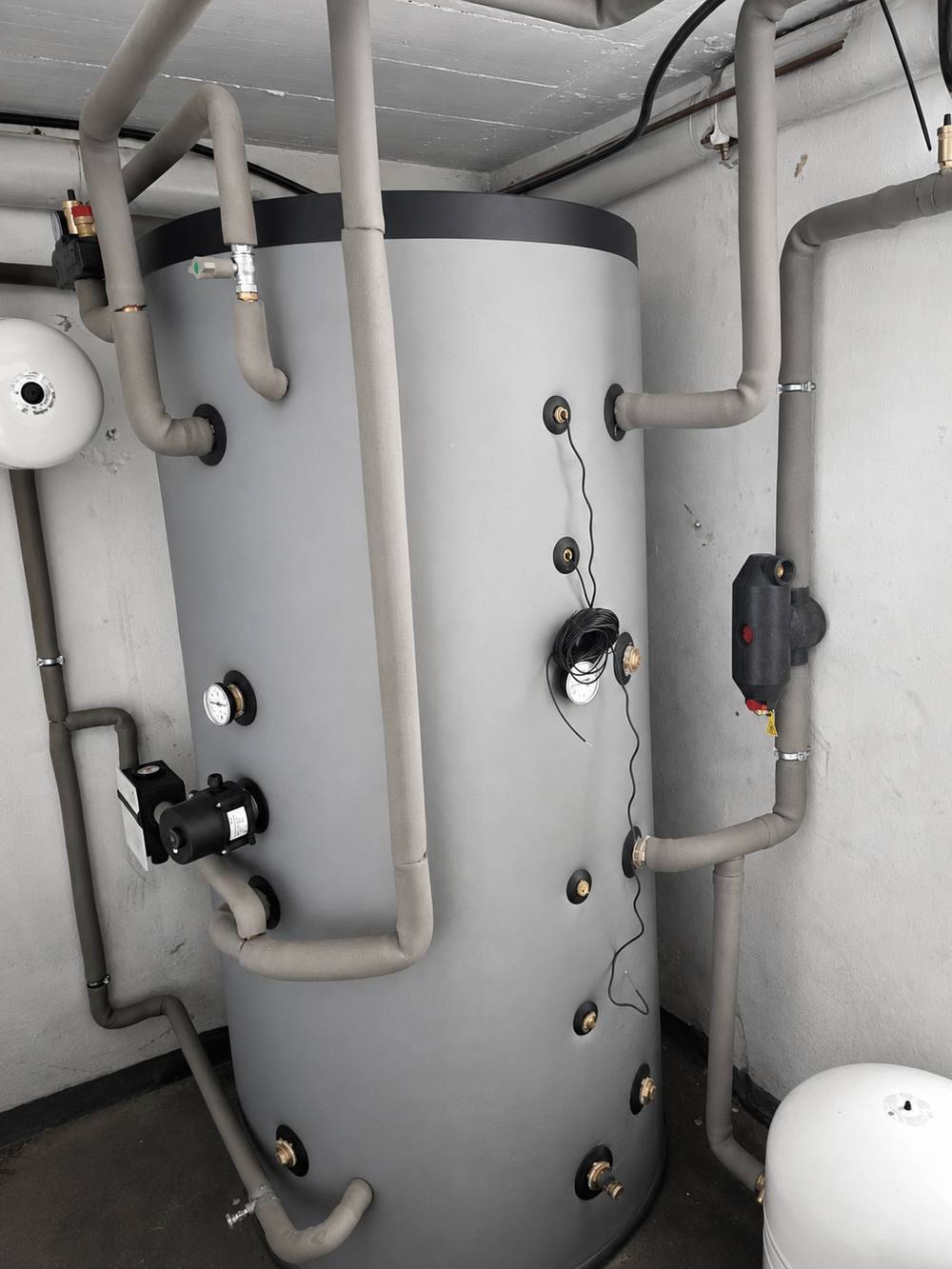 Pufferspeicher mit gedämmter Heizungsverrohrung im Technikraum